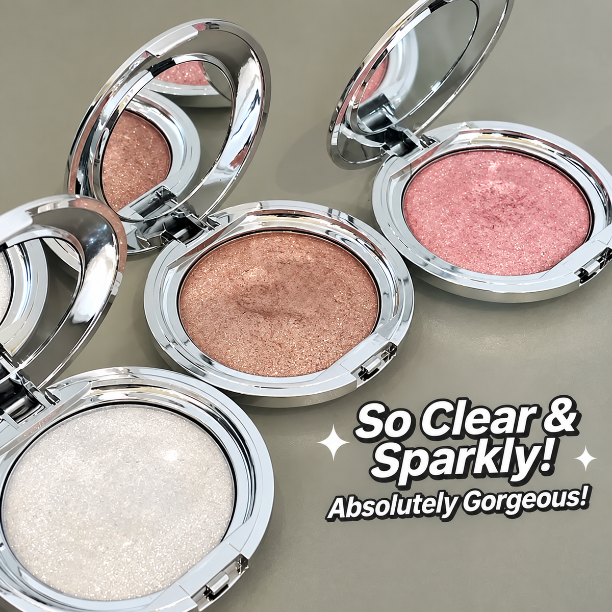 Four round compact eyeshadows with silver lids are arranged on a neutral gray background. The compacts are open, showing the shimmering pressed powders in rose gold, pink, champagne, and icy white.