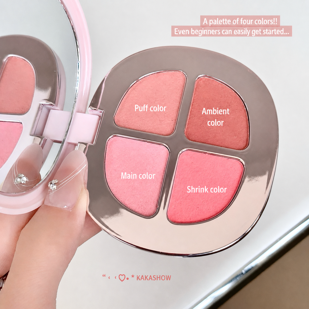 A hand holds an open makeup palette with four blush shades labeled 'Puff color', 'Ambient color', 'Main color', and 'Shrink color'. The compact has a shiny metallic rose-gold finish and a pink interior, with a small mirror visible on the left.